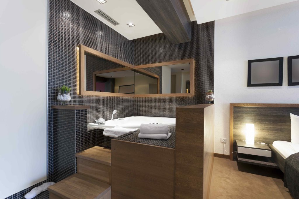 Modern hotel room featuring a private in-room hot tub, minimalist design, soft lighting, and bedroom view
